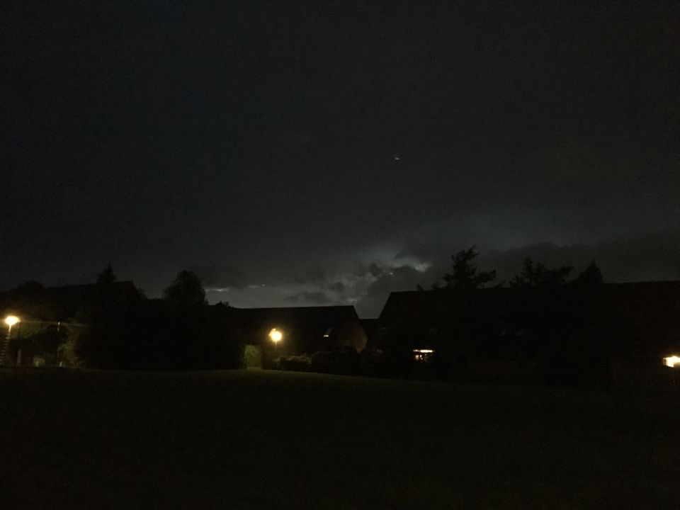 Fel licht tussen de donkere wolken en silhouet van immens vliegtuig + ronde bol foto